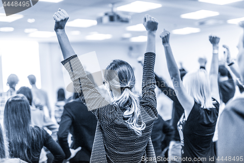 Image of Participants of interactive motivational speech feeling empowered and motivated, hands raised high in the air.