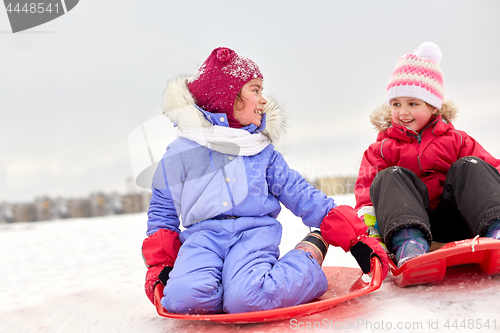 Image of happy little girls on sleds outdoors in winter