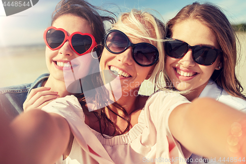 Image of group of smiling women taking selfie on beach