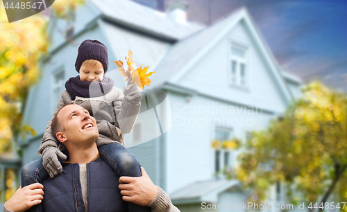 Image of father and son with autumn maple leaves over house