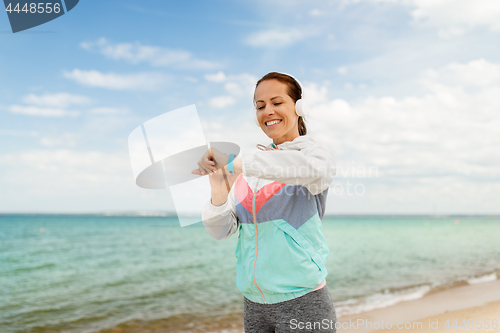 Image of woman with headphones and fitness tracker on beach