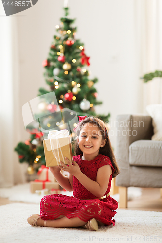 Image of happy girl with christmas gift at home