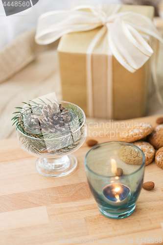 Image of christmas fir decoration, candle, cookies and gift