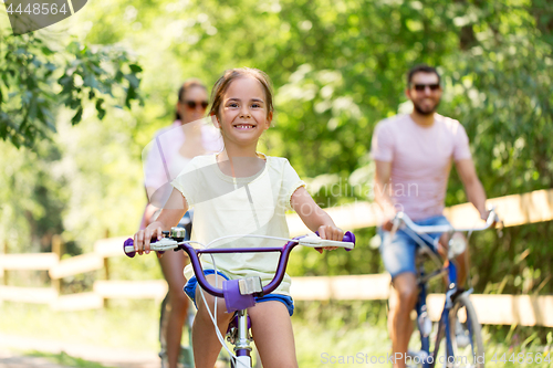 Image of happy family riding bicycles in summer park