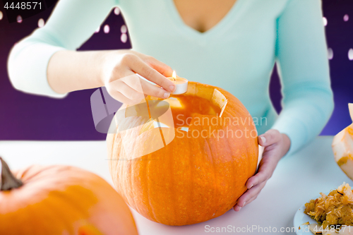Image of hands with candle and halloween pumpkin