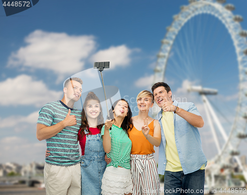 Image of friends taking selfie over ferry wheel in london