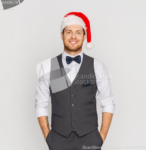 Image of happy man in santa hat and suit at christmas