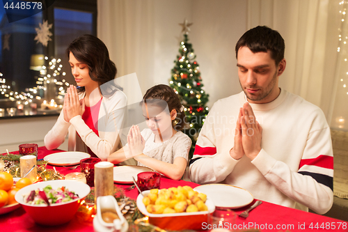 Image of family praying before meal at christmas dinner