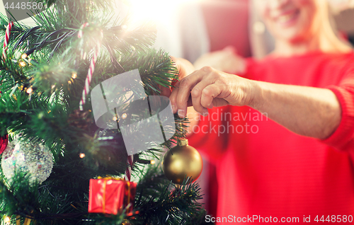 Image of close up of senior woman decorating christmas tree