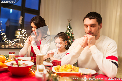 Image of family praying before meal at christmas dinner