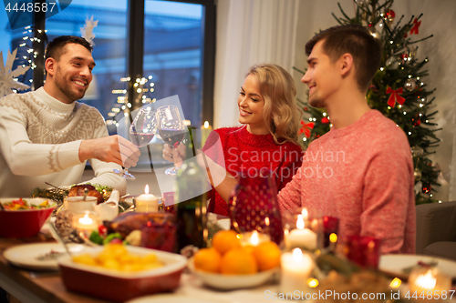 Image of happy friends drinking red wine at christmas party