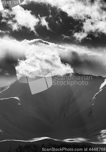 Image of Black and white view on evening snow mountains with sunlit cloud