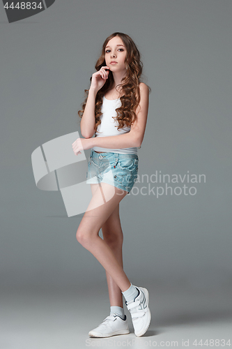 Image of Full length of young slim female girl in denim shorts on gray background