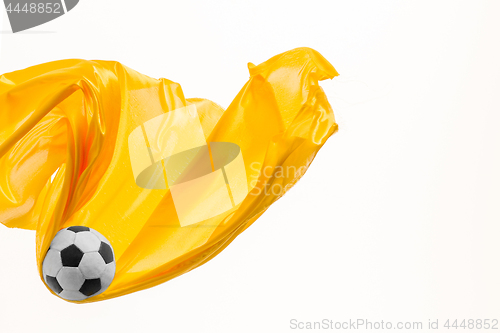 Image of Soccer ball and Smooth elegant transparent yellow cloth isolated or separated on white studio background.