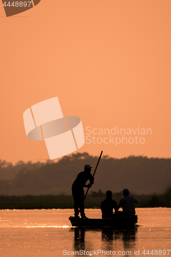 Image of Men in a boat on a river silhouette