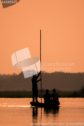 Image of Men in a boat on a river silhouette