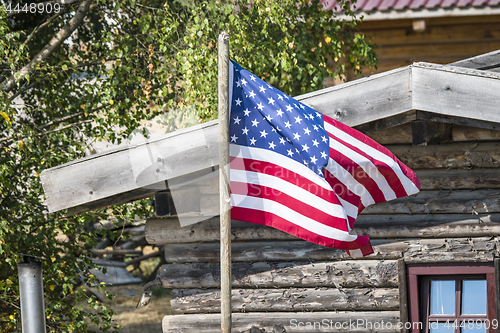 Image of The flag of USA outside a wooden cabin