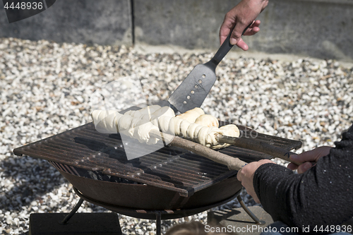 Image of Dough on a grill wrapped around wooden sticks