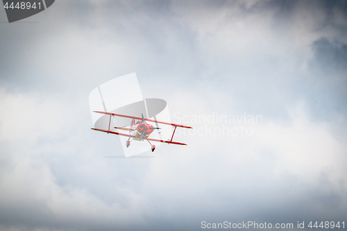 Image of Red propeller airplane flying among the clouds