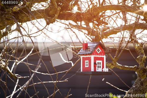 Image of Red birdhouse barn hanging in a tree
