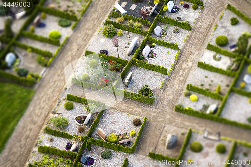 Image of Cemetery with green hedges and gravestones decorated with flower