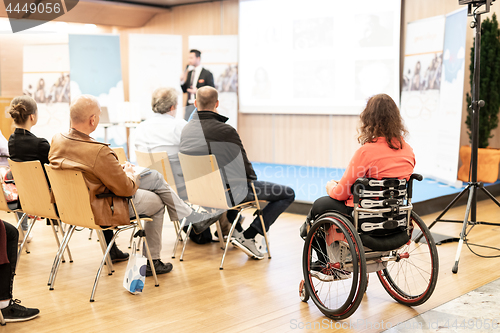 Image of Rear view of nrecognizable woman on a wheelchair participating at business conference talk.