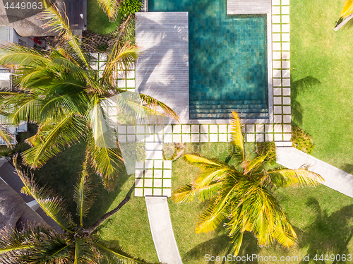 Image of Aerial view of luxury hotel resort with swimming pool with stair and wooden deck surrounded by palm trees.