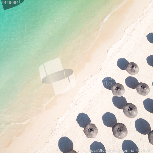 Image of Aerial view of amazing tropical white sandy beach with palm leaves umbrellas and turquoise sea.