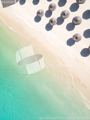 Image of Aerial view of amazing tropical white sandy beach with palm leaves umbrellas and turquoise sea.