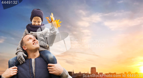 Image of father carrying son with autumn leaves in city