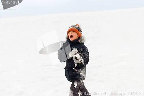 Image of happy little boy playing with snow in winter