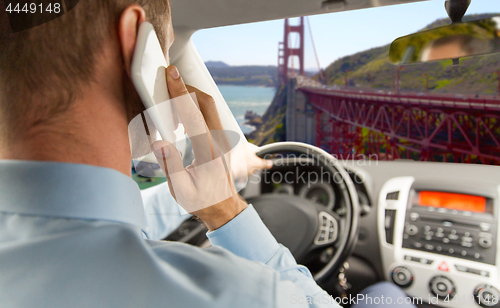 Image of businessman calling on smartphone and driving car