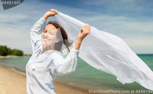 Image of happy woman with shawl waving in wind on beach