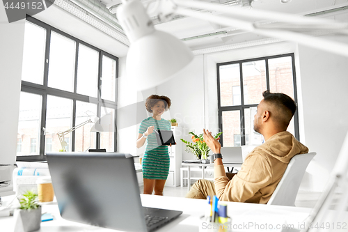 Image of woman showing tablet pc to creative team at office