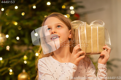 Image of smiling girl with christmas gift at home