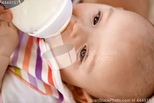 Image of close up of baby sucking milk formula from bottle