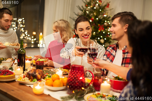 Image of happy friends drinking red wine at christmas party