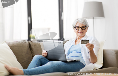 Image of senior woman with laptop and credit card at home