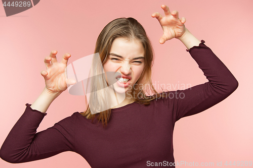 Image of Angry, playful and scares woman is teaseing on the pink studio background and looking at camera