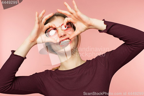 Image of Woman smiling with perfect smile and white teeth on the pink studio background.