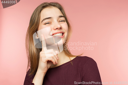 Image of Woman smiling with perfect smile and white teeth on the pink studio background and looking at camera