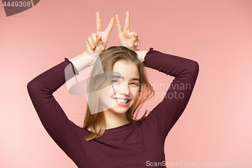 Image of Woman smiling with perfect smile and white teeth on the pink studio background and looking at camera