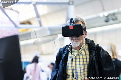 Image of Senior man wearing virtual reality goggles watching virtual reality presentation.