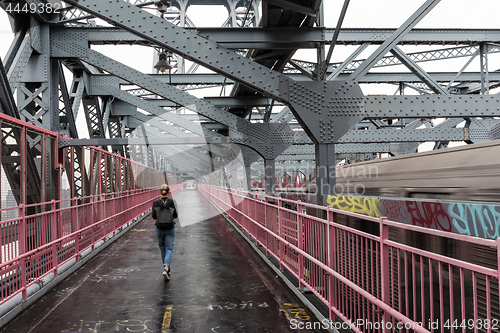 Image of Solo casual woman walking the cycling lane on Williamsburg Bridge, Brooklyn, New York City, USA