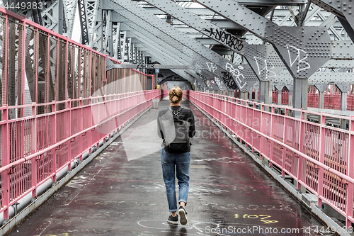 Image of Solo casual woman walking the cycling lane on Williamsburg Bridge, Brooklyn, New York City, USA