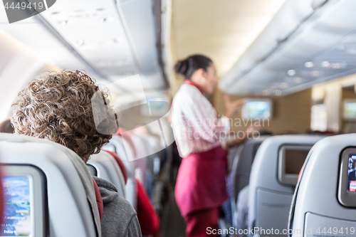 Image of Interior of commercial airplane with passengers on their seats during flight.