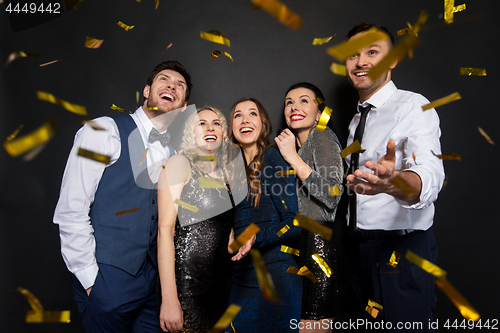 Image of happy friends at party under confetti over black