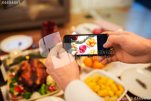 Image of hands photographing food at christmas dinner