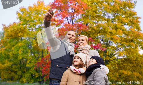 Image of family taking selfie by camera in autumn park