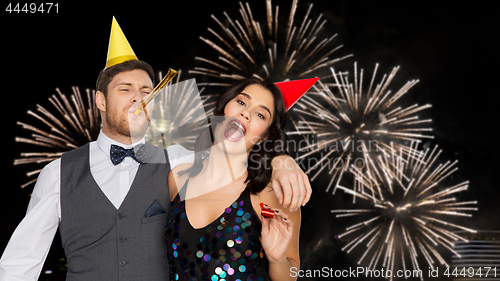 Image of happy couple with party blowers having fun